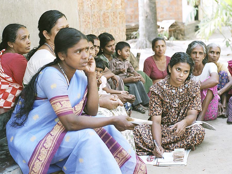 Members of a microfinance group meeting, passbooks in hand